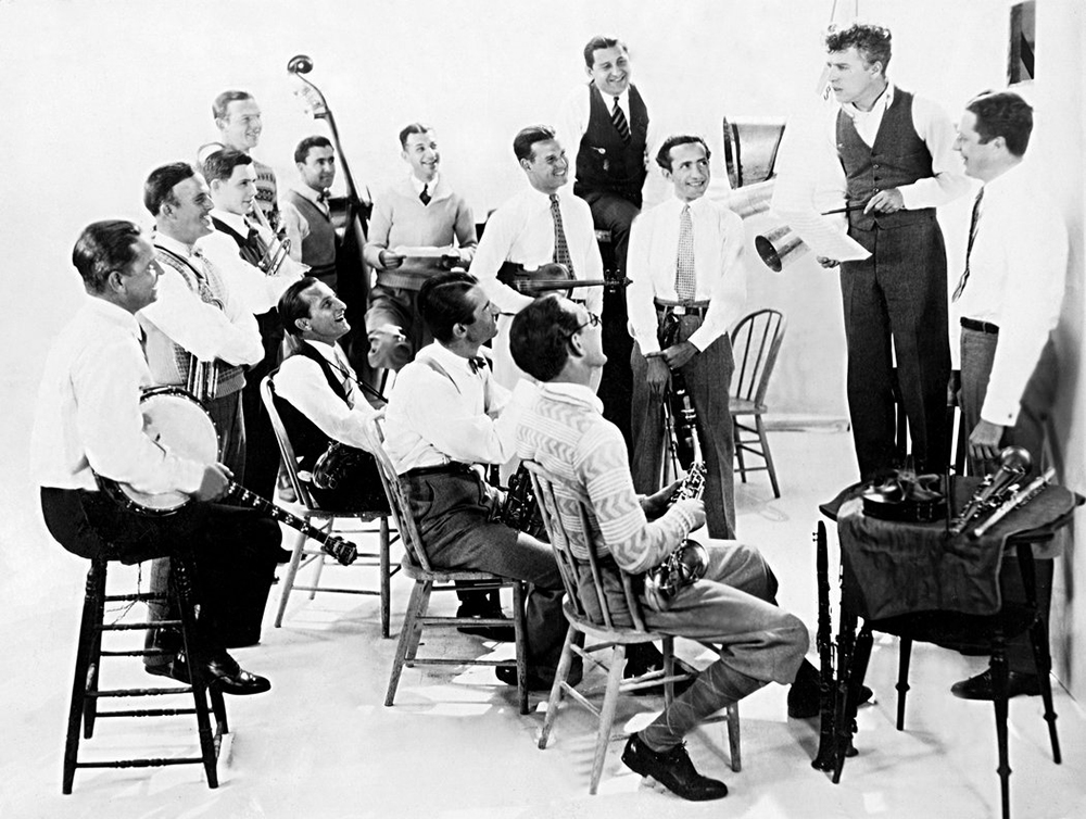 Чарли Чаплин (стоит на стуле) обсуждает с участниками оркестра California-Brunswick Orchestra композиции к фильму «Золотая лихорадка», 1925 год/ Фото: Everett Collection/ Фото с сайта nytimes.com